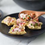 shrimp ceviche on wooden spoon with black plate and chips