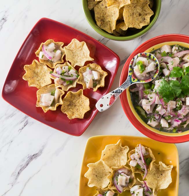 A red serving plate with a large bowl of tilapia ceviche.