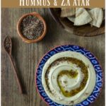 A blue bowl with hummus and wooden bowl with pita chips.