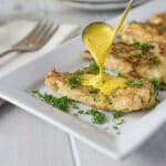 Chicken in creamy saffron sauce on a white plate.